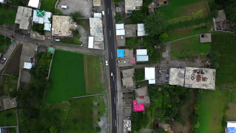 Dramatic-drone-shot-following-a-tuk-tuk-on-the-Karakoram-Highway-Pakistan-in-a-small-town,-downward-angle-aerial-shot