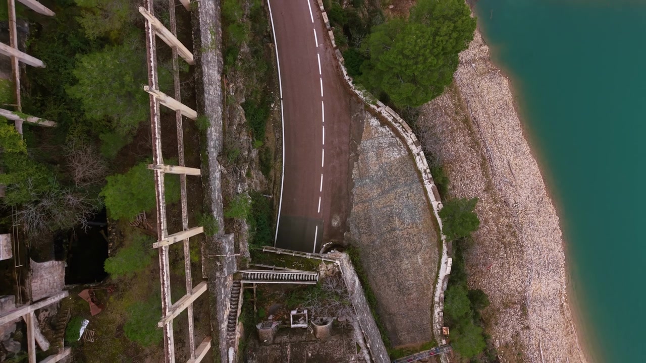Vue aérienne de la route du barrage de Benagéber le long de la rivière Turia en Espagne, avec l'eau turquoise du réservoir, un rivage rocheux, une végétation luxuriante et une infrastructure en béton