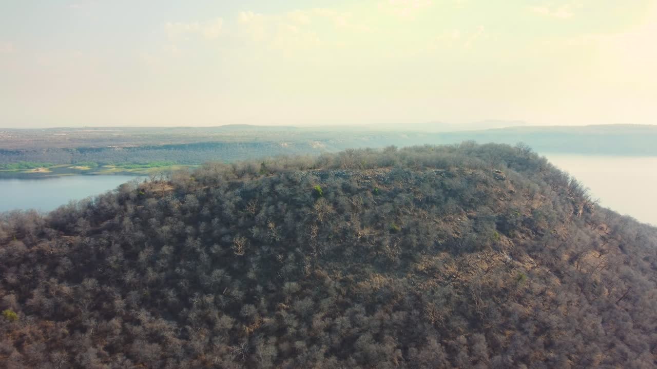 tomada aérea de un drona de una colina forestal con un embalse en el fondo en tighra gwalior en madhya pradesh, india