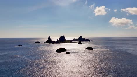 Toma-Aérea-Acercándose-A-Muchas-Pequeñas-Islas-Rocosas-Cerca-De-La-Isla-De-Las-Orquídeas-Durante-El-Día-Soleado-Con-Reflejo-En-El-Agua-Azul