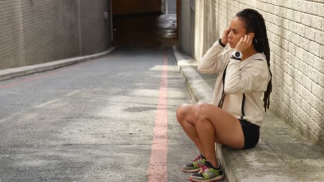 Side-view-of-young-African-American-woman-wearing-earphones-in-the-city-4k