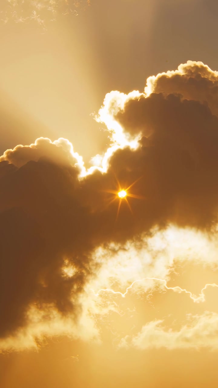 Vertical video: Sun peeking through cloud gaps causing backlit cloud casting sunset rays and flare