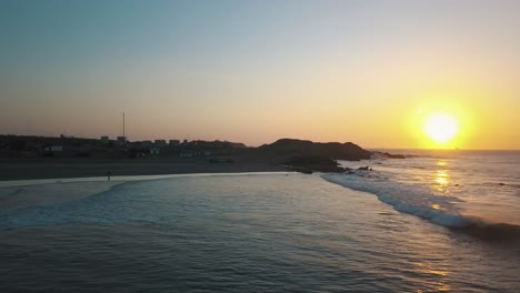 Surfing-at-sunset-near-Lobitos,-Peru.-Aerial-orbiting