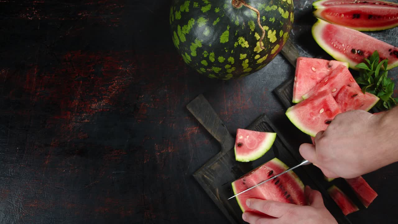 las manos del hombre aplastaron la sandía en la tabla de cortar.