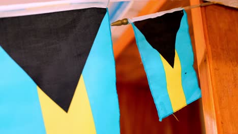 bahamian flags fluttering in the wind, wood backdrop, patriotic display