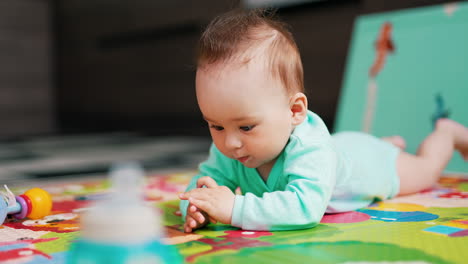 funny cute baby with cute hairdo lies on the floor. lovely child claps his hands on the floor and smiles. blurred backdrop.