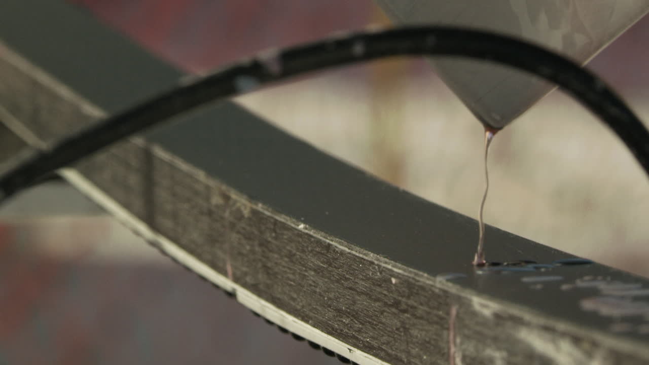 Detail shot of melted wax dripping onto sled ski surface smoothing process