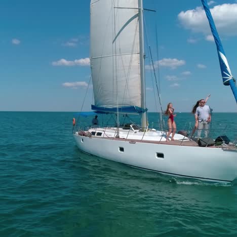 people rest on a sailboat. voyage on a yacht in the open sea. girls dancing on a ship while floating on water. happy summer vacation. aerial view