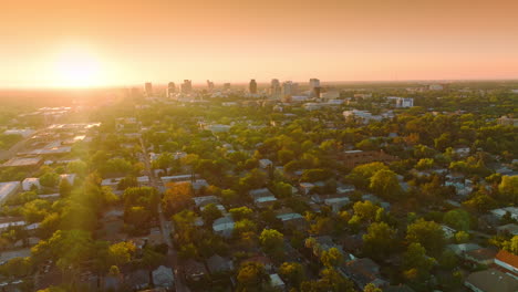 last rays of setting sun over the beautiful green city. few multi-storied buildings standing out at the backdrop of orange sky.