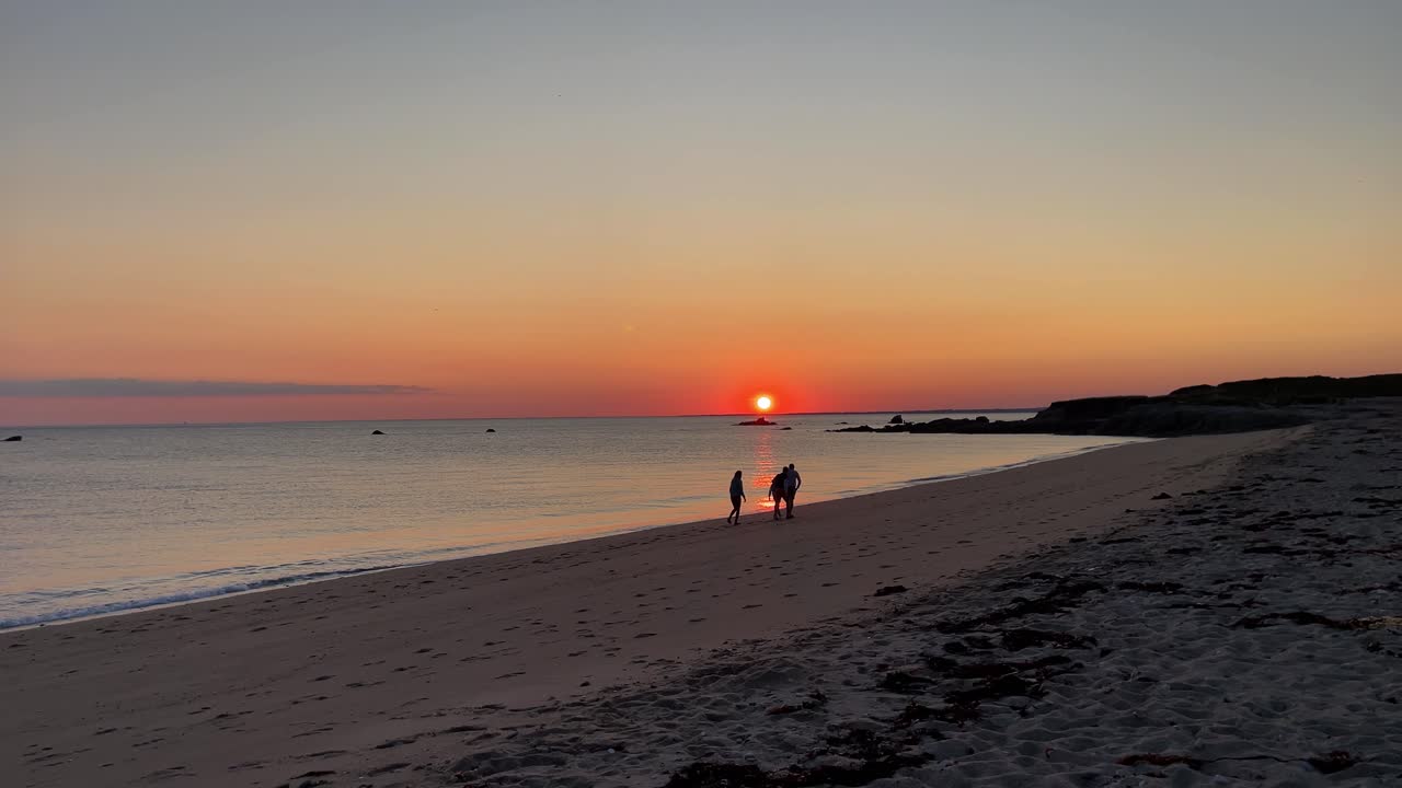 고독한 해변에서 놀라운 일몰을 산책하는 가족