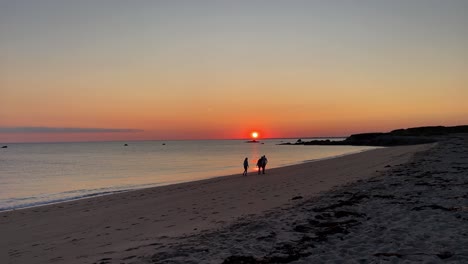Family-taking-a-walk-at-amazing-sunset-on-a-solitary-beach