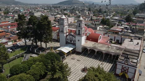 aerial-orbit-view-of-some-birds-flying-near-of-old-stone-church-in-Almoloya,-Mexico