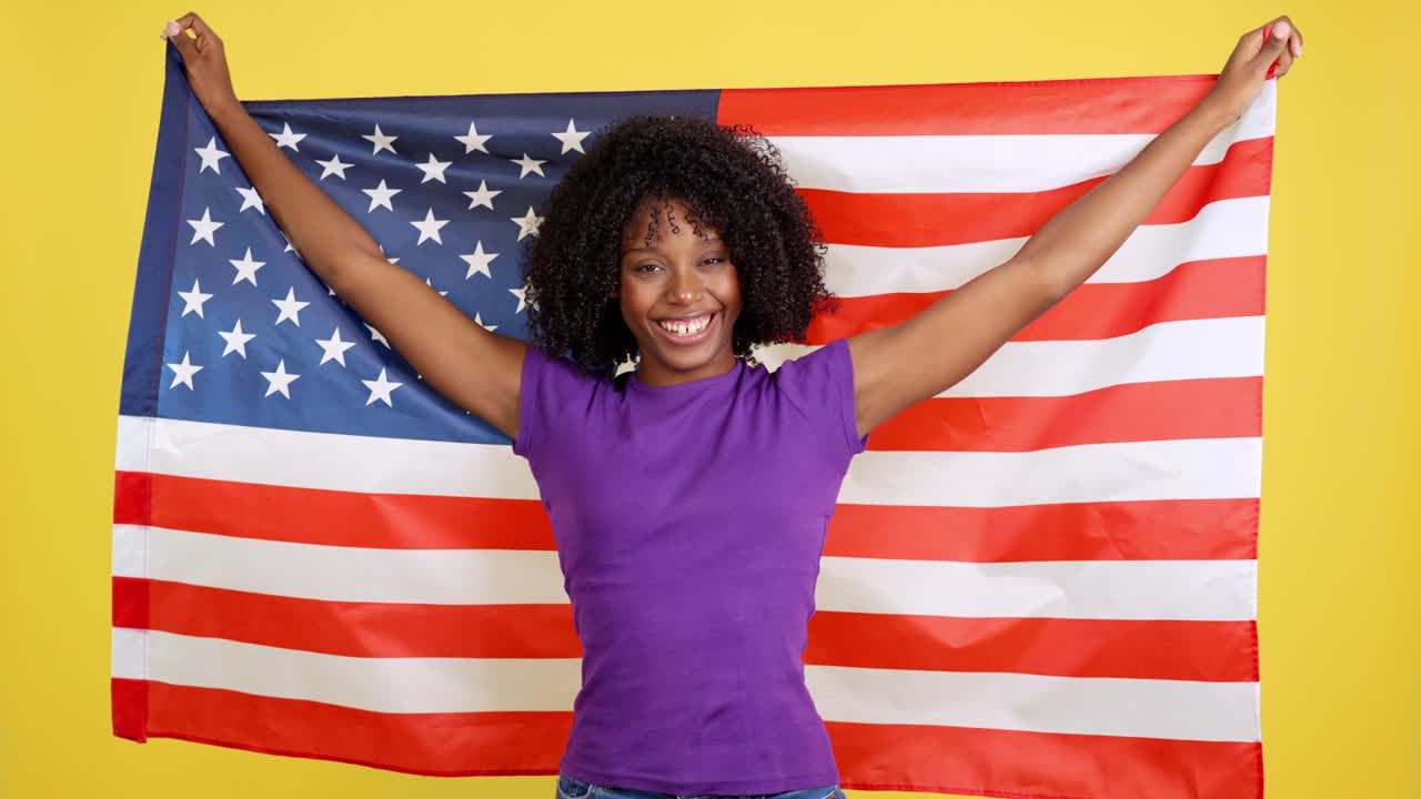 Femme souriante tenant un drapeau américain sur fond jaune