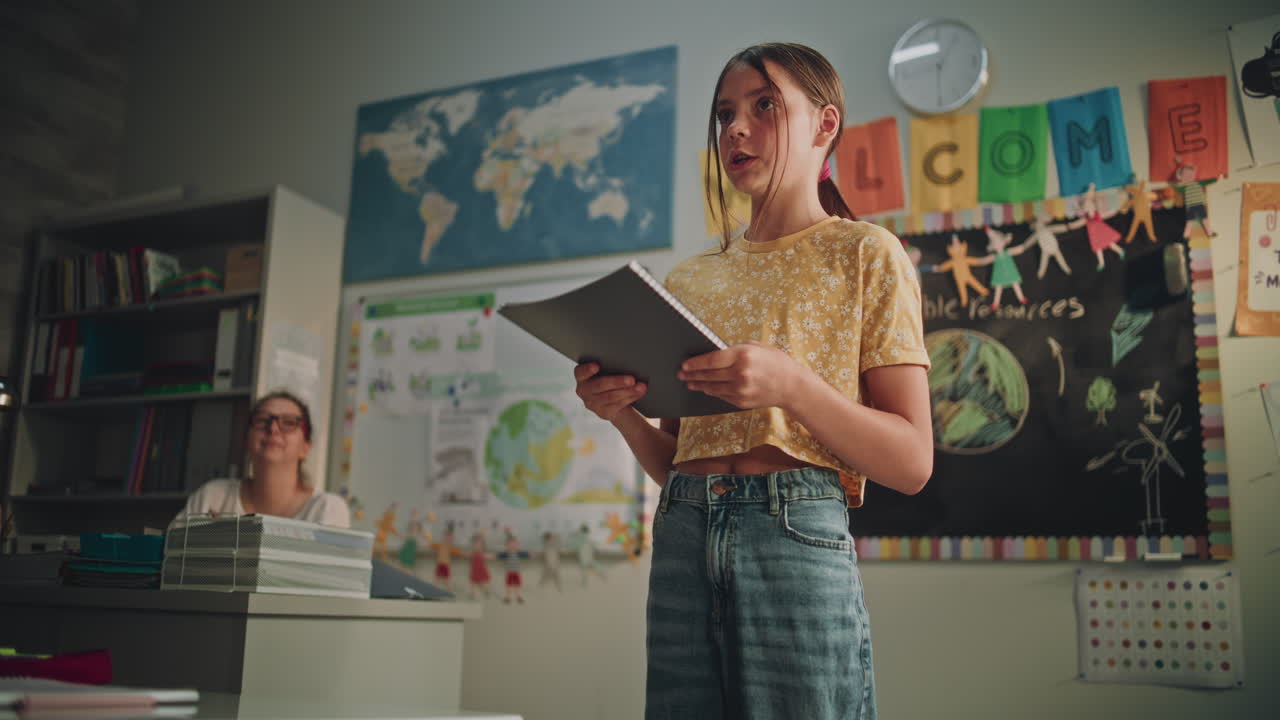 Primary School Girl Holding Notebook Speaking Showcasing Knowledge of Ecology