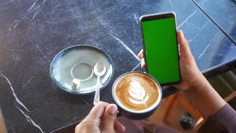 woman enjoying coffee and using mobile phone in a cafe