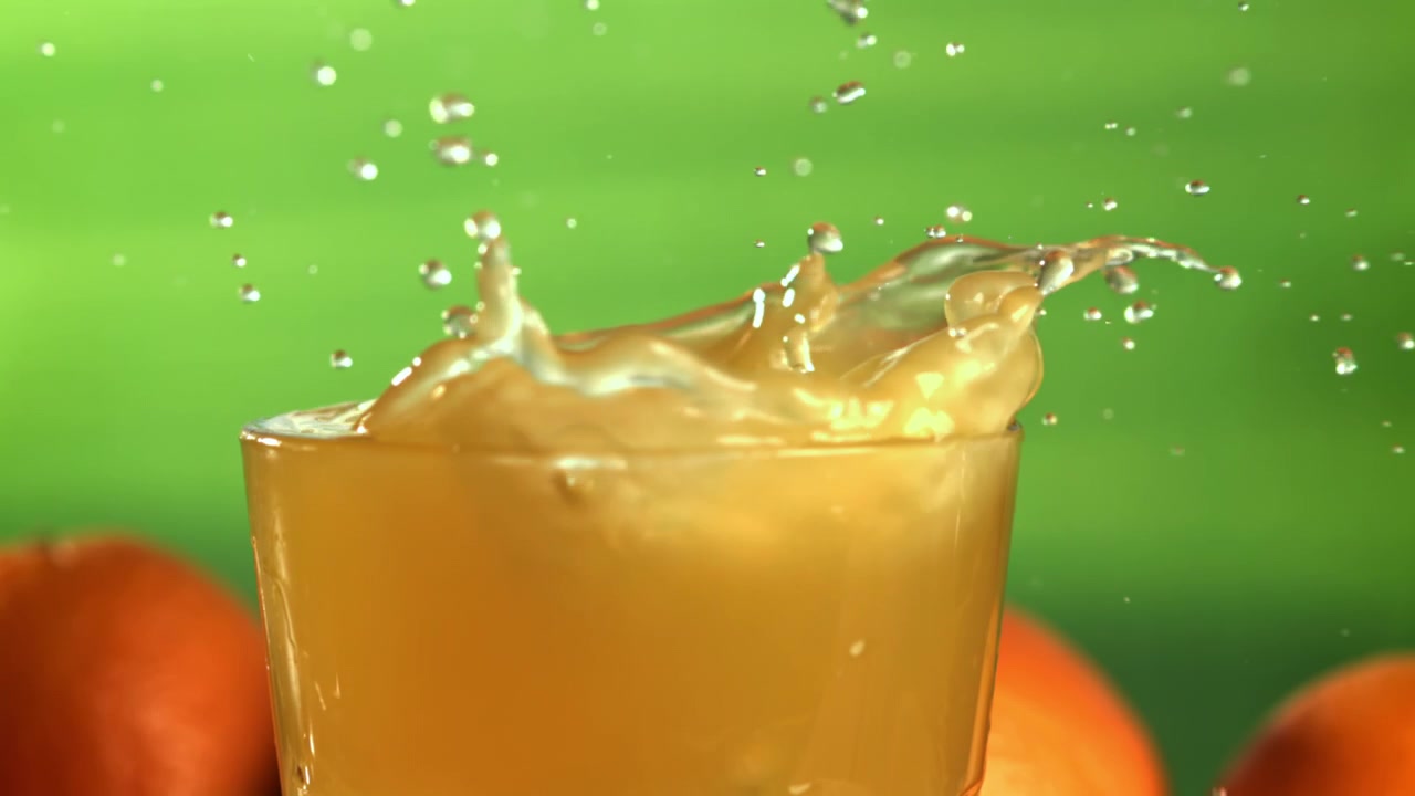 Slow Motion Ice Cube Splashing into Orange Juice