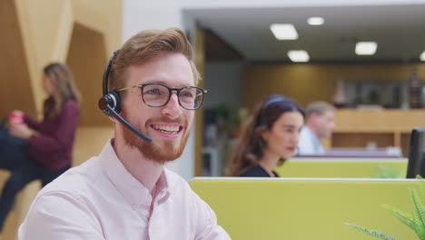 portrait of businessman wearing headset talking to caller in customer services centre