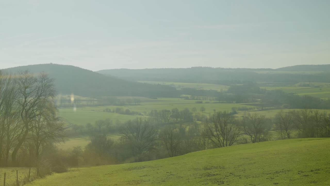 Inside a German ICE high-speed train, a view of fields and hills seen from the window