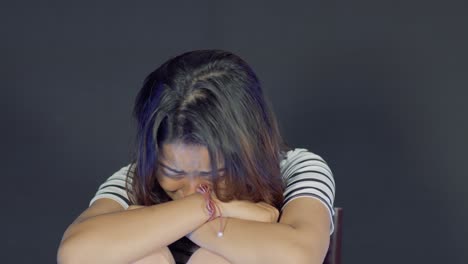 Crying-woman-alone-in-horror-room,sitting-on-chair