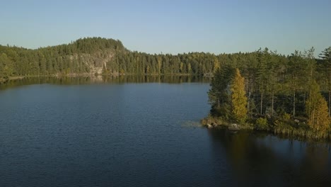 finnish lake with beautiful island and rocky shore, autumn trees and deep blue water