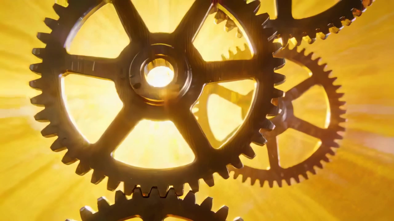 Rotating three meshing metal gears revealing starburst in studio closeup, casting golden lens flare
