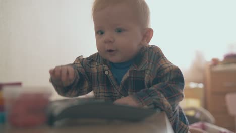 Kleiner-Junge-Erreicht-Die-Fernbedienung-Des-Fernsehers-Auf-Einem-Niedrigen-Holztisch