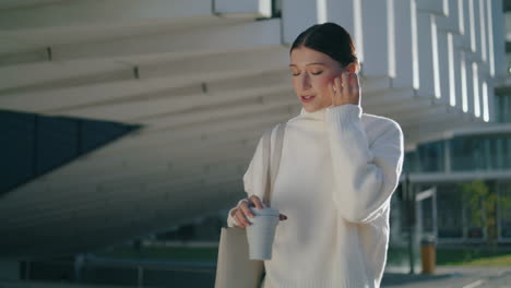 girl talking phone earbuds walking city close up. woman using headphone vertical