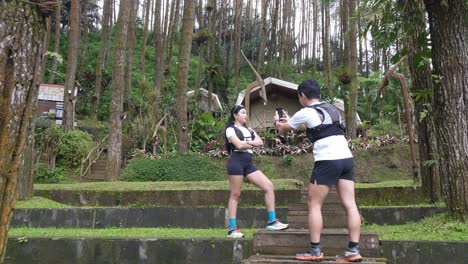 asian couple taking photos during outdoor adventure in forest
