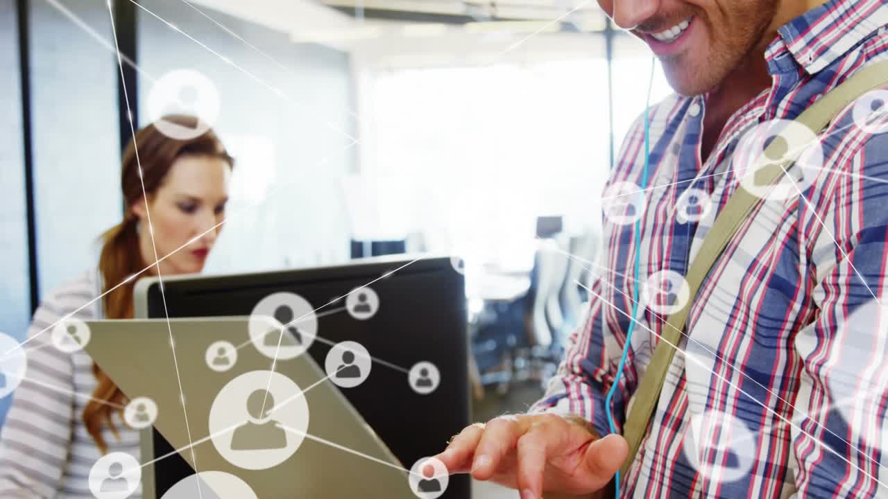 Uomo che tiene in mano un laptop, digita e fa apparire icone di rete scintillanti in un ufficio tecnologico, indossando cuffie e connettendosi.