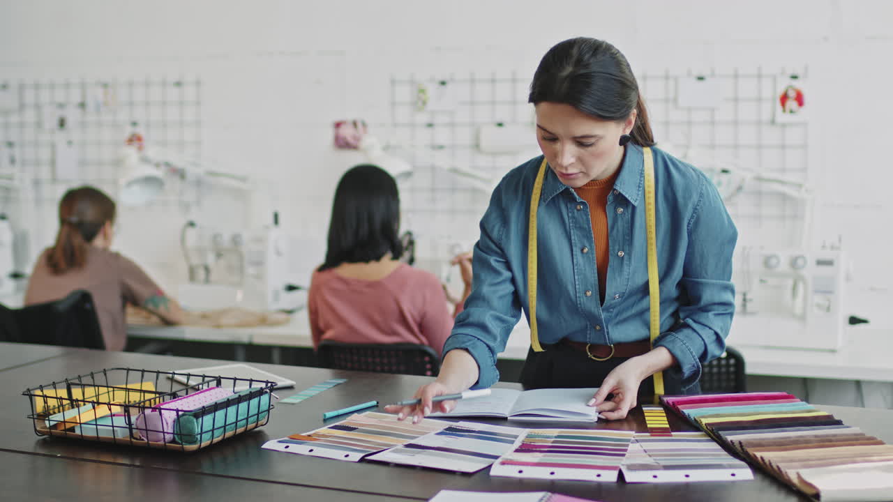 Female Fashion Designer Writing Ideas in Notebook