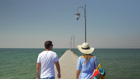 una pareja gana una bolsa rodante caminando por el muelle.
