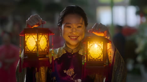 smiling woman holding illuminated traditional lanterns