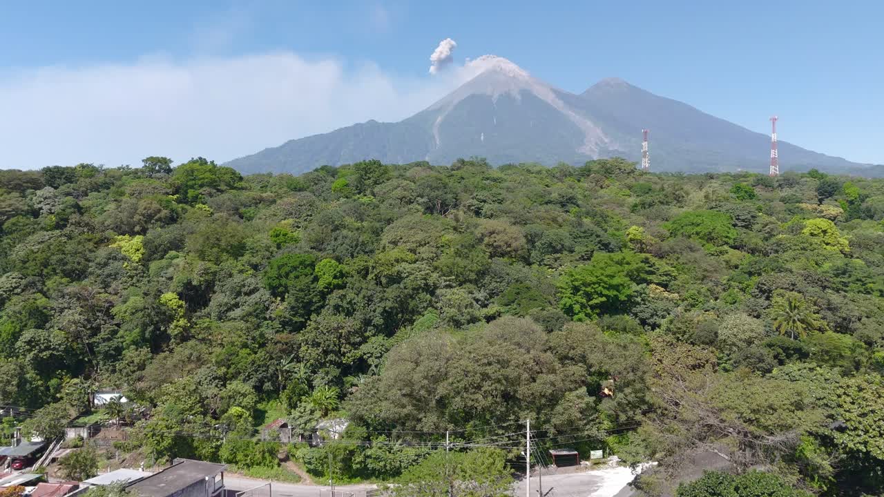 Striking view of Volcan de Fuego emitting amoke during an eruption with lush green forest in the foreground
