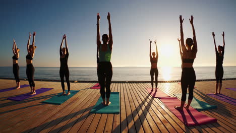 yoga class on a beach pier at sunrise
