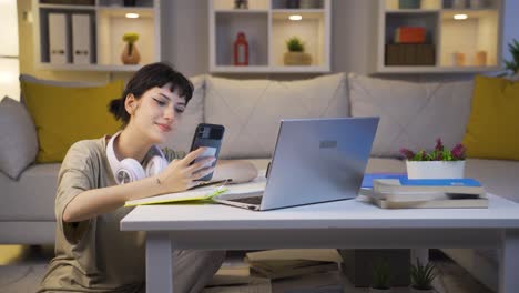 Young-woman-using-social-media-on-phone-laughing-at-night-at-home.