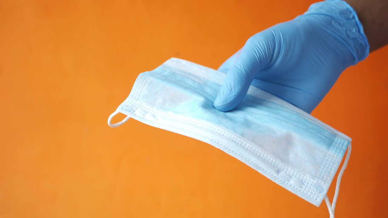 mano con guante sosteniendo una máscara facial