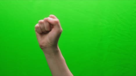 close-up of a fist raised up on a green background, shooting a hand gesture