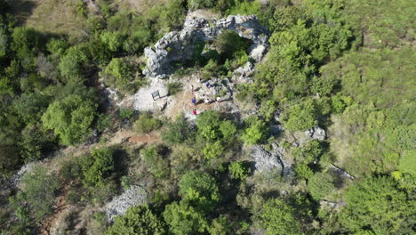 hiking tourists look around naturally wind eroded stone arch, aerial shot