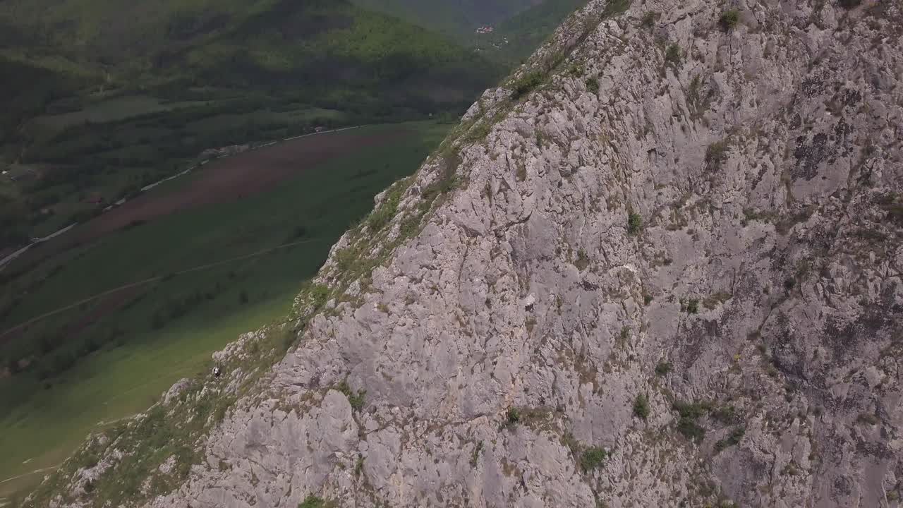 Aerial View Of Backpacker Climbing High Rocky Mountain Towards Summit With Mountains Landscape In Horizon