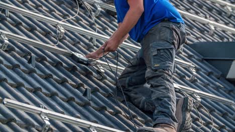 close up shot of of male worker connecting electric cable of solar panels on rooftop