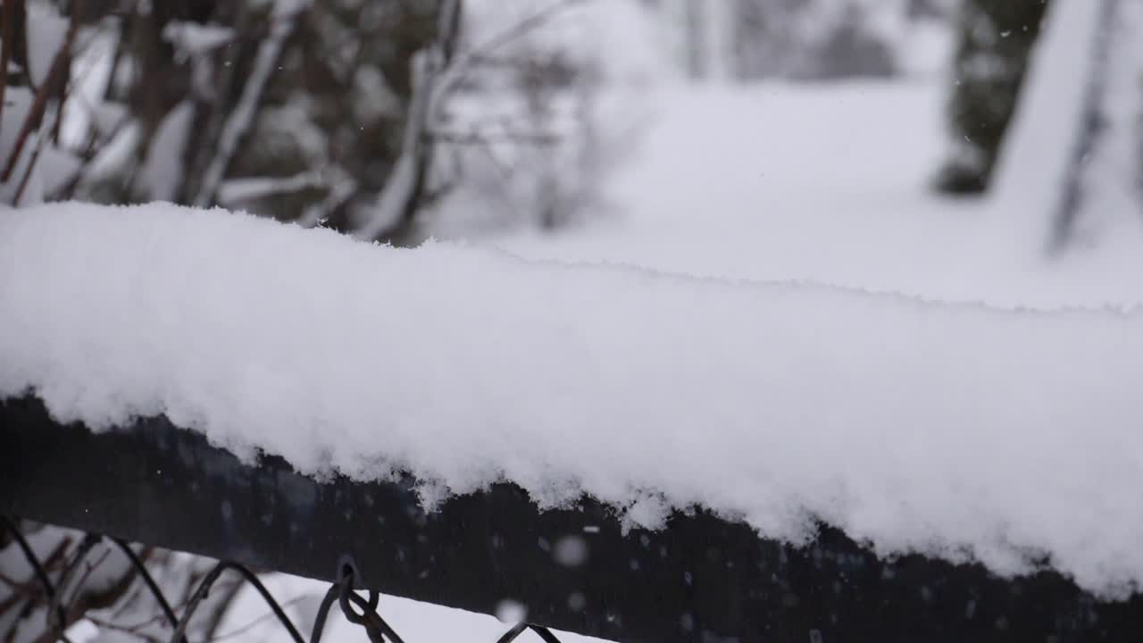 fresh snow falling over industrial fence - slow motion - slide down to upp