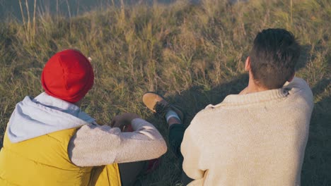 happy men talk sitting on dry grass at campsite in evening