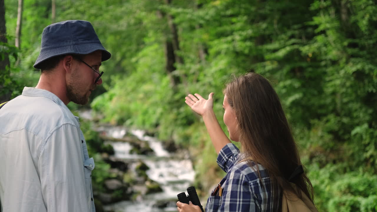 una pareja caminando en un bosque junto a un arroyo.
