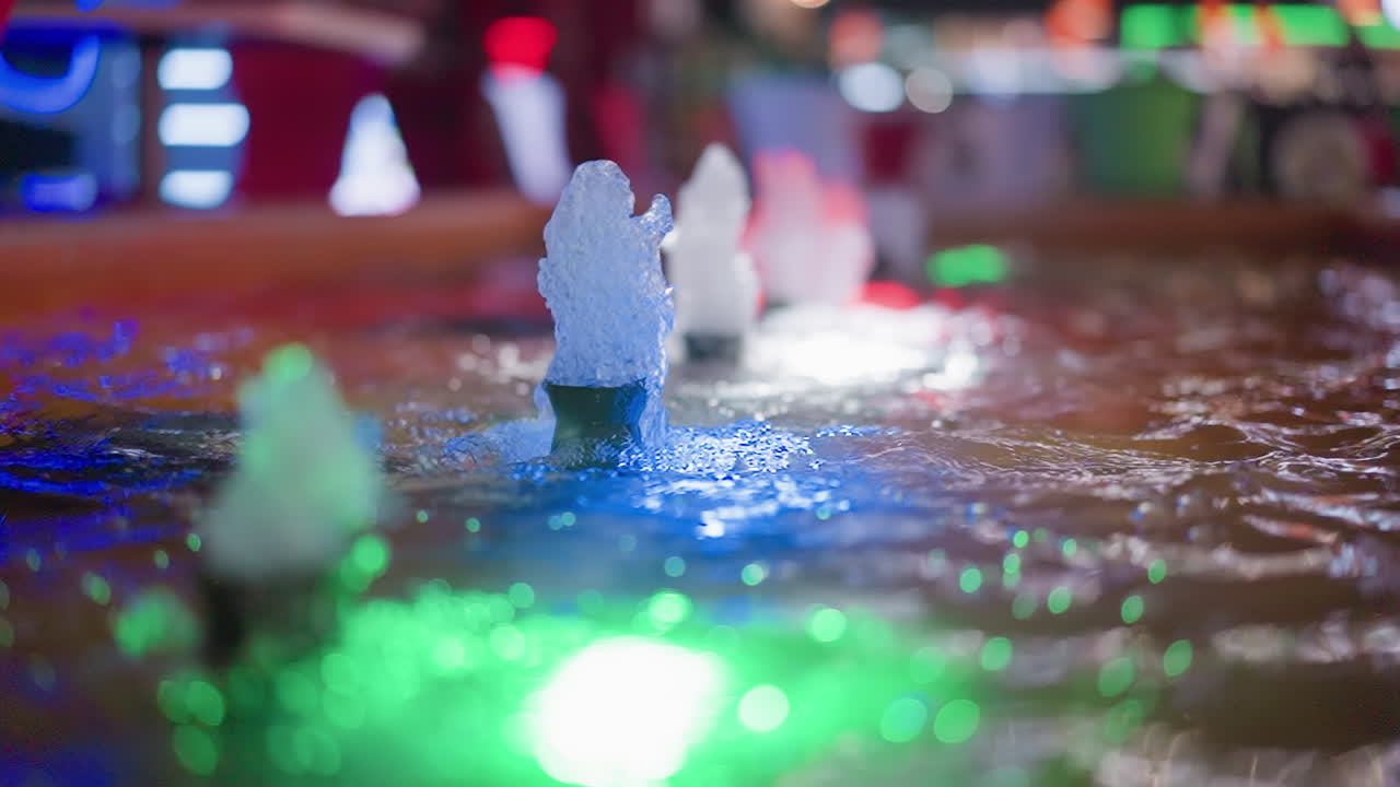 밤에는 녹색, 파란색, 색의 불빛으로 활기차고 역동적인 분위기를 조성하는 다채로운 조명된 물 분수들의 근접한 모습