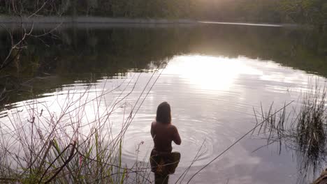 half naked woman standing in idyllic lake with reflections