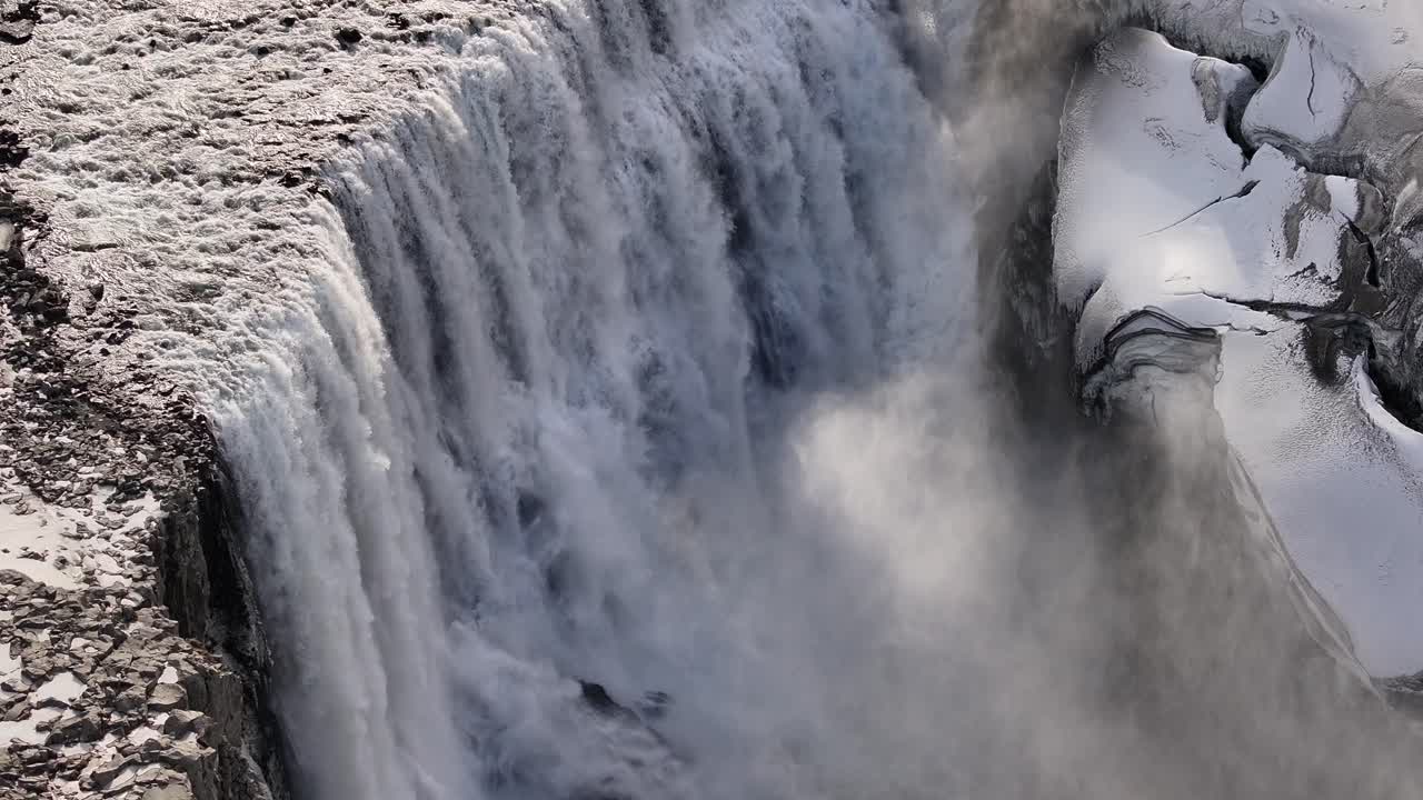 Drone view of Dettifoss waterfall in Iceland thundering down into a snowy canyon.