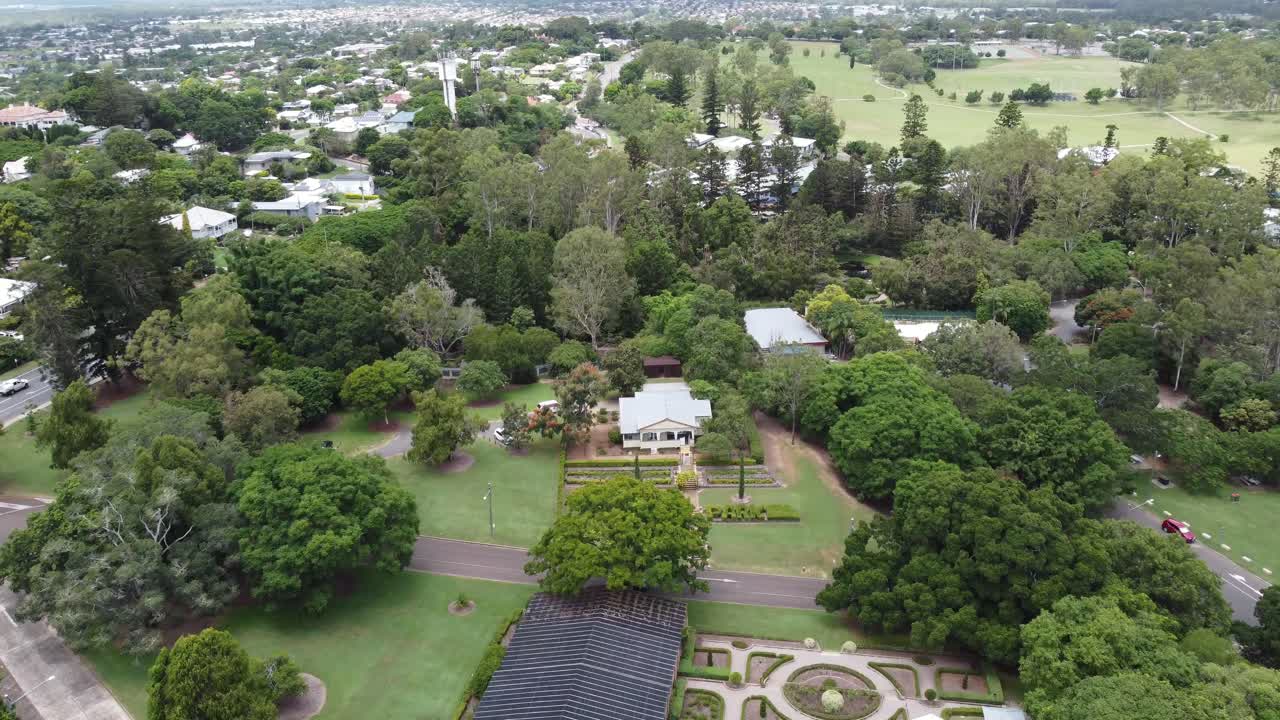 오스트레일리아의 한 지역 마을에 있는 큰 녹색 공원의 4k 공중 드론 이 공원의 상업 건물을 향해 날아가고 있다.