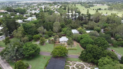 4k aerial drone shot of a large green park in a regional town in australia flying towards commercial buildings in the park