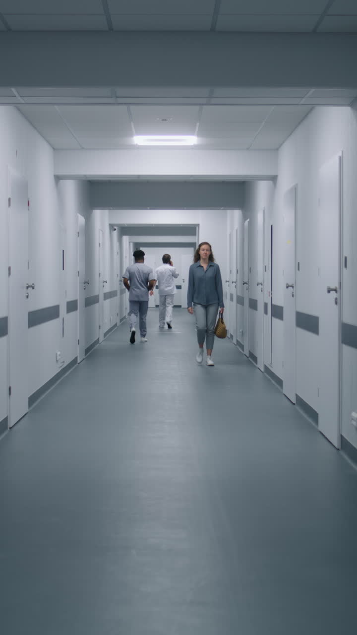 African American Physician Walks Hospital Corridor. African American physician walks medical centre corridor and greets with colleague. Female patient goes to appointment with doctor. Multi ethnic healthcare specialists work in clinic. Vertical shot