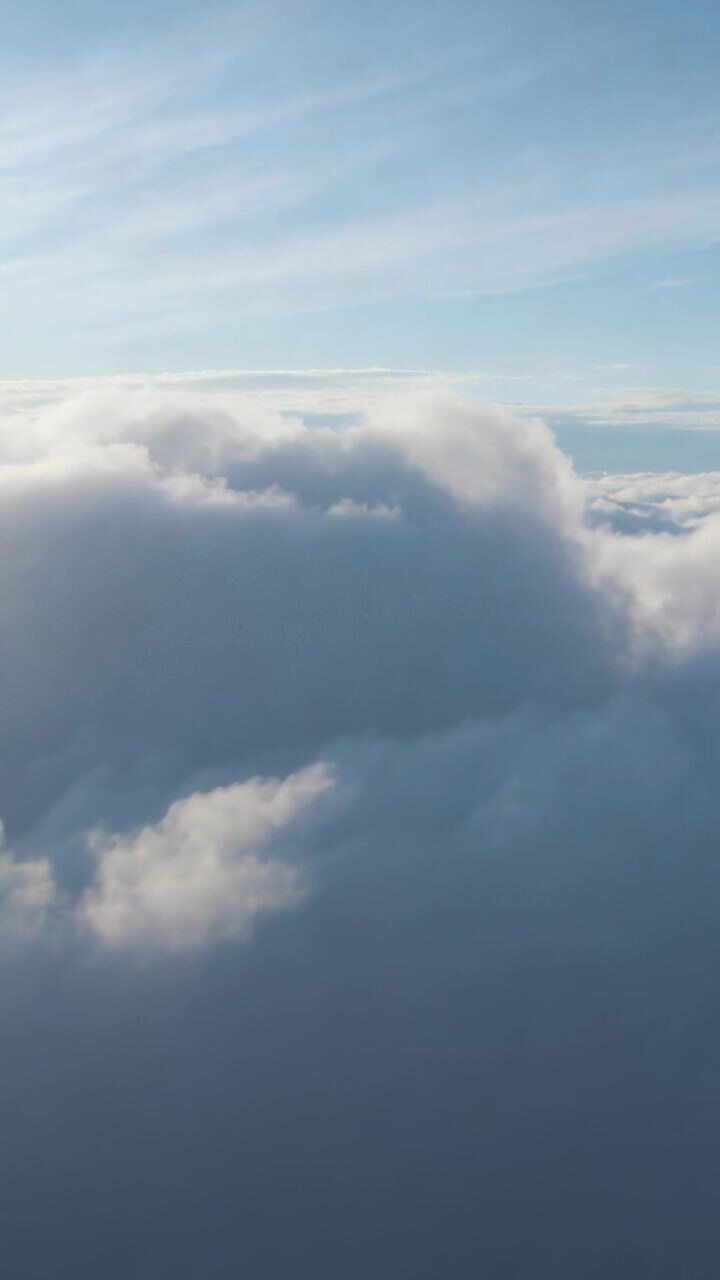 Vertical video: Drone motion panning above clouds, revealing cumulus contours aiding weather tech